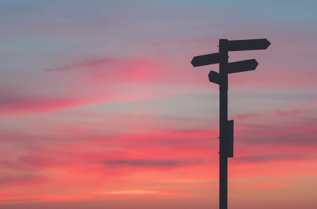 A sunset with a signpost at a crossroads 