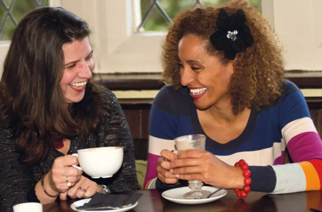 Loretta Andrews and Ruth Hill laughing and holding coffee cups