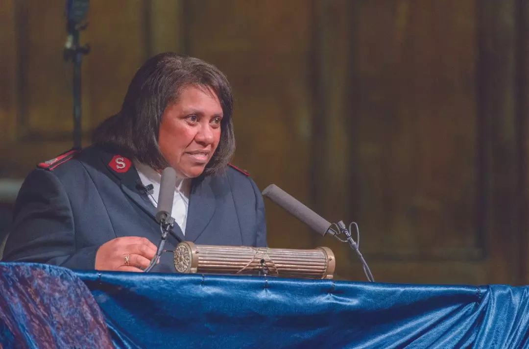 A photo of Althea Bawden speaking from a lectern wearing Salvation Army uniform