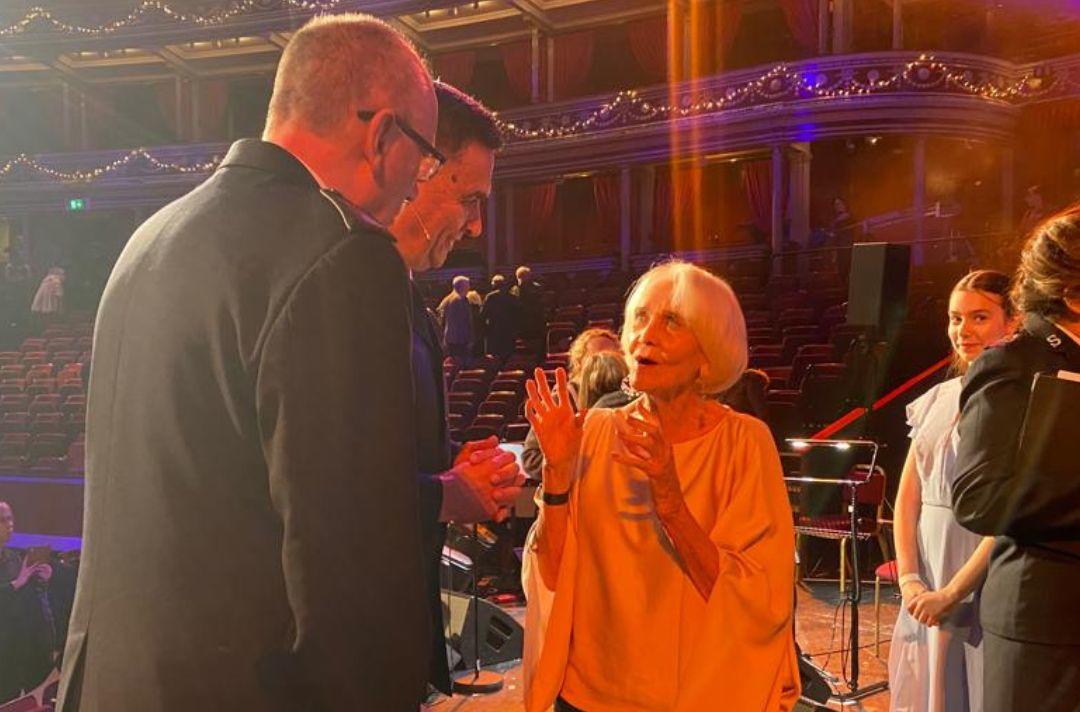 A photo of Dame Sheila Hancock speaking with Commissioner Anthony Cotterill and Lieut-Colonel Dean Pallant on stage at the end of the concert