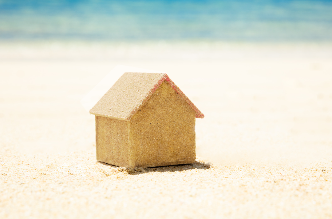 Photo shows a small house on a beach
