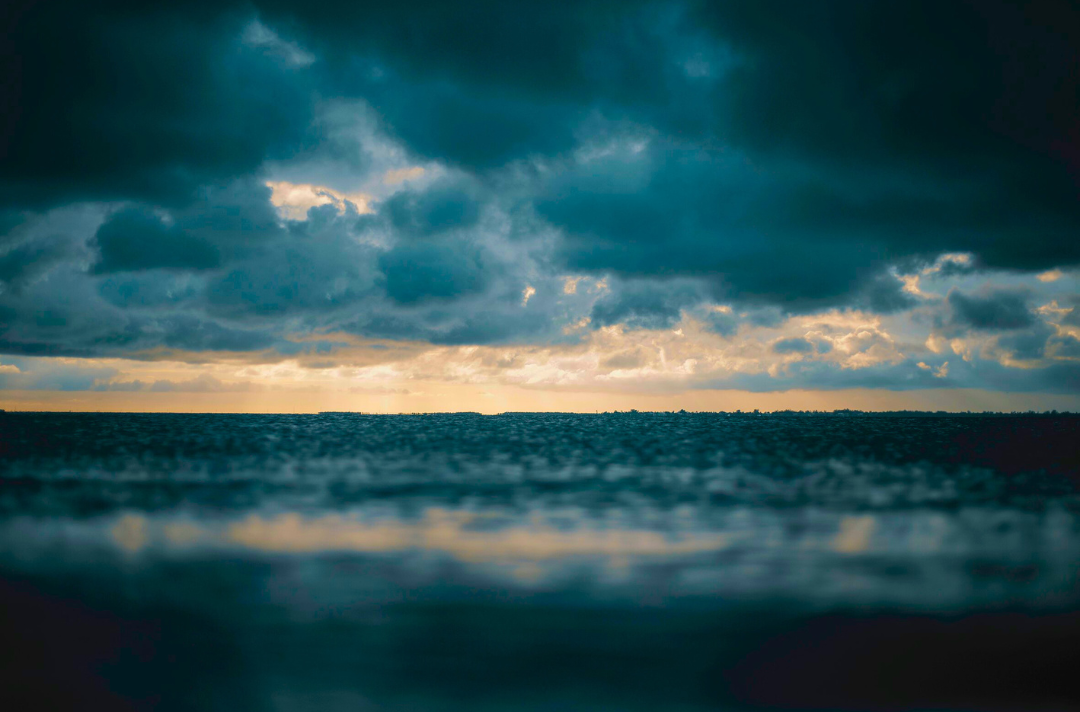 Photo shows a calm sea with brooding storm clouds.