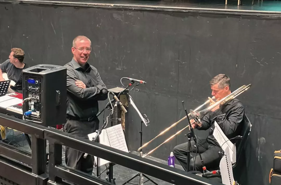A photo of the band in the band pit of a theatre