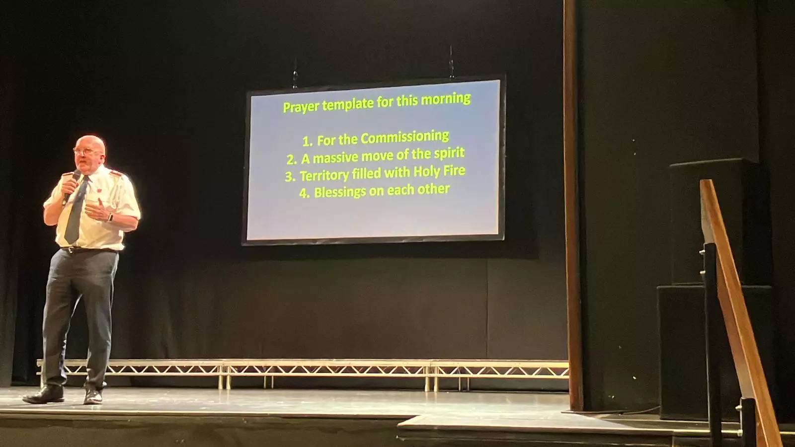 A photo of Gary Lacey leading prayers on a stage