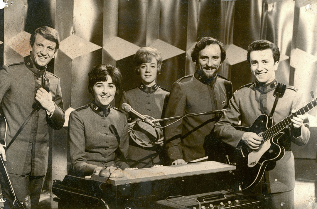A sepia tone photo shows the Joystrings smiling at the camera.