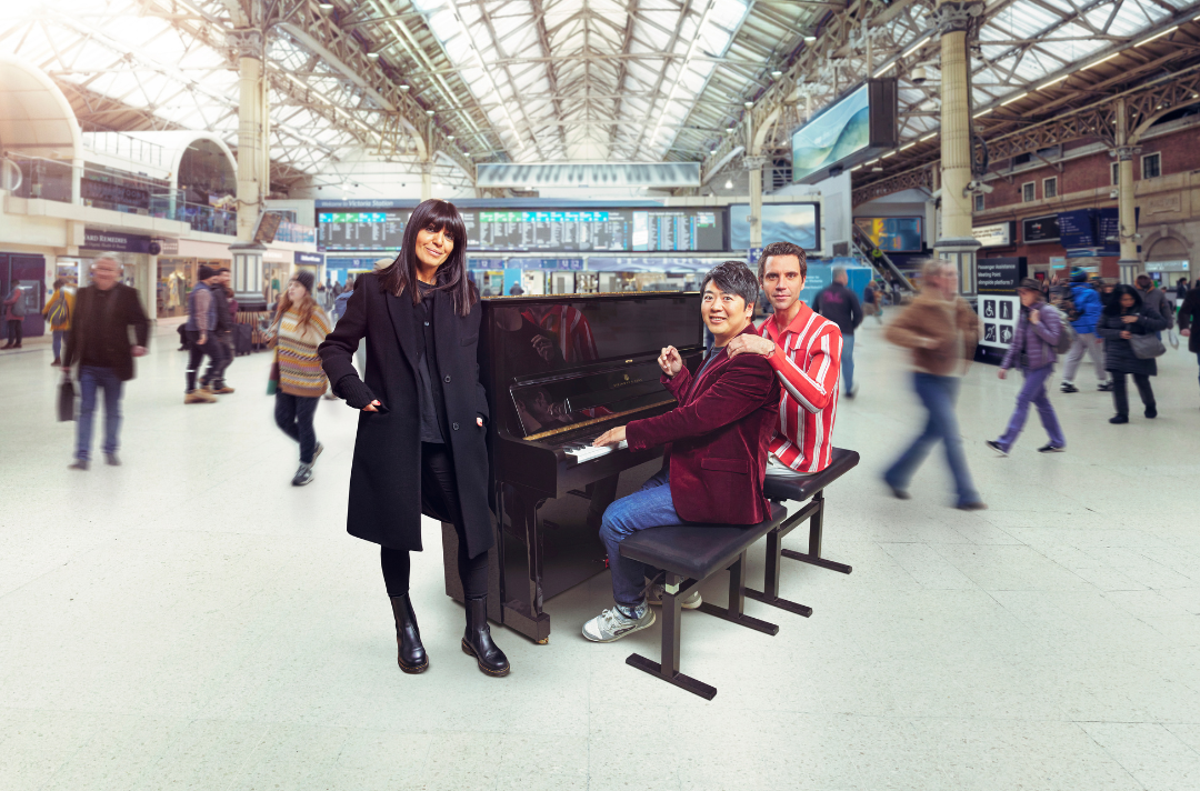 A photo shows people gathered around a piano in a busy train station.
