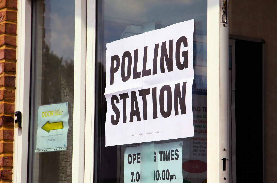 A photo shows a sign displaying the text 'polling station' stuck to a window.