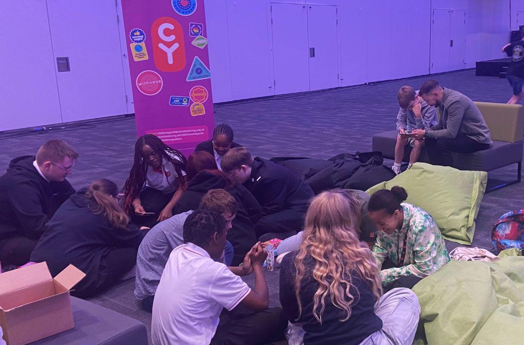 A group of teenagers playing card games on the floor at Together 2024