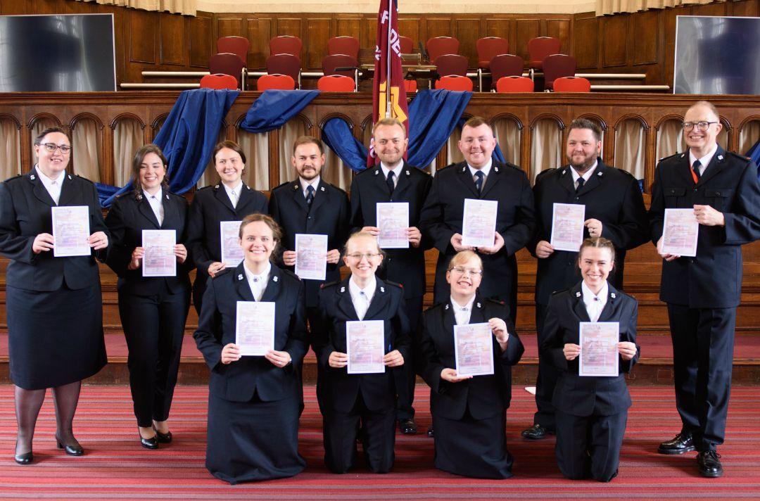 A photo shows the cadets of the Defenders of Justice session holding up their signed copies of the Officer's Covenant.