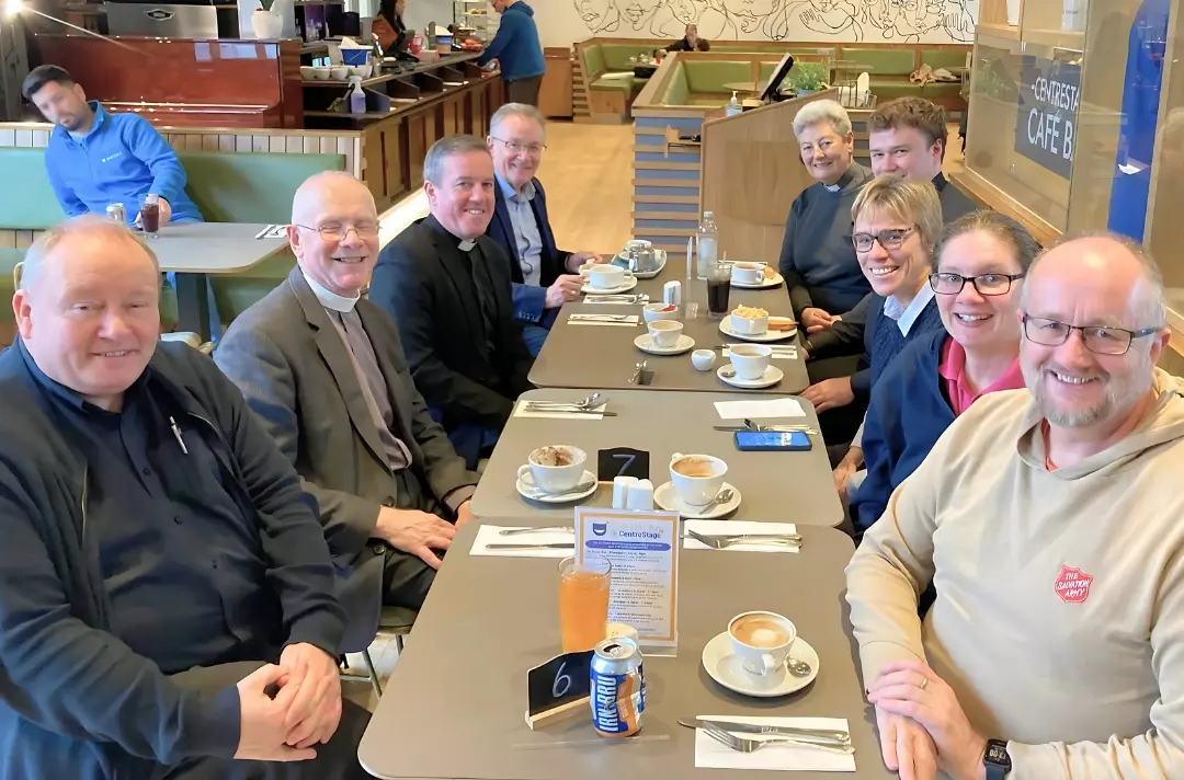 A photo shows a group of people sat around a table in a café.